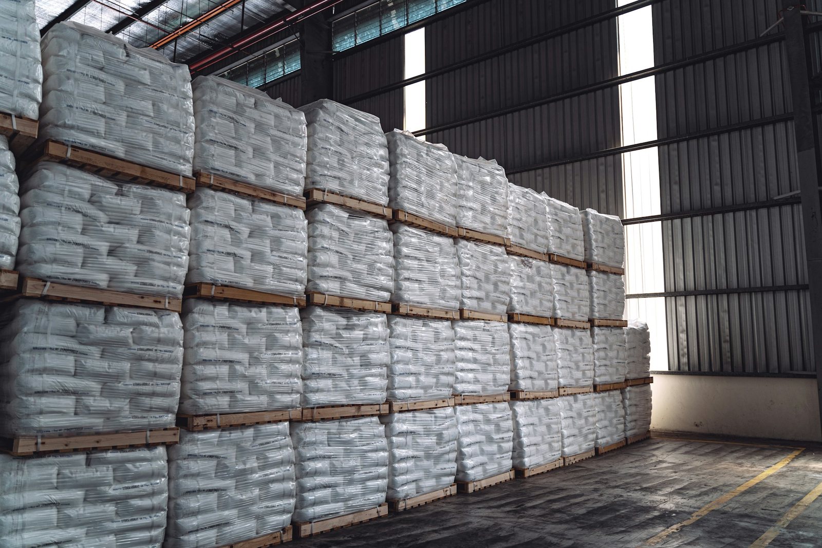 White sacks stacked on pallets inside a warehouse